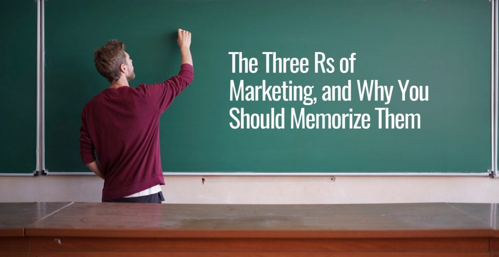A man in a classroom writing to a black board