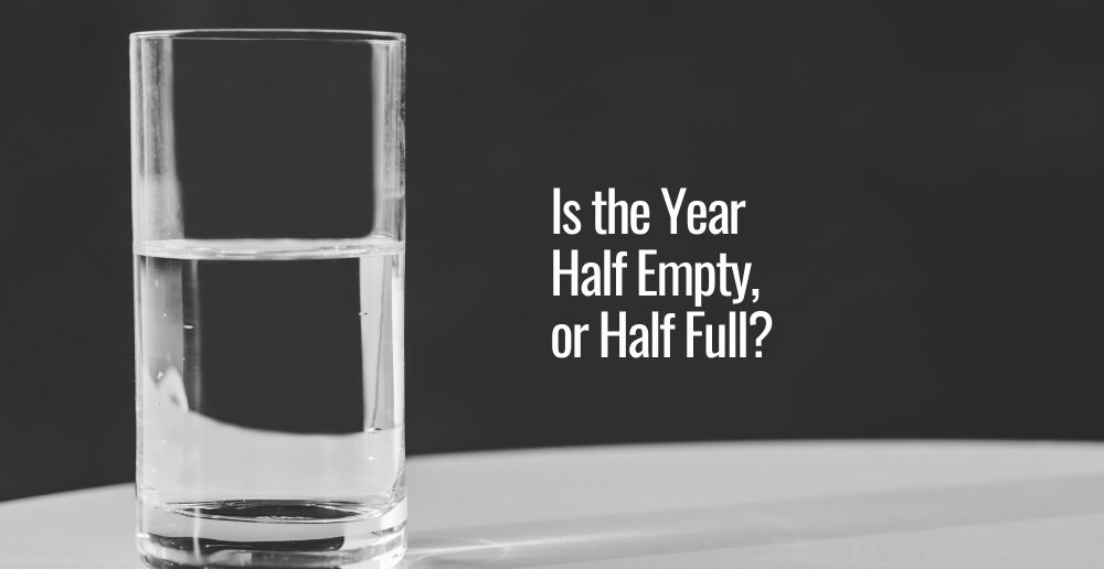 A black background with a drinking glass with half a water in it