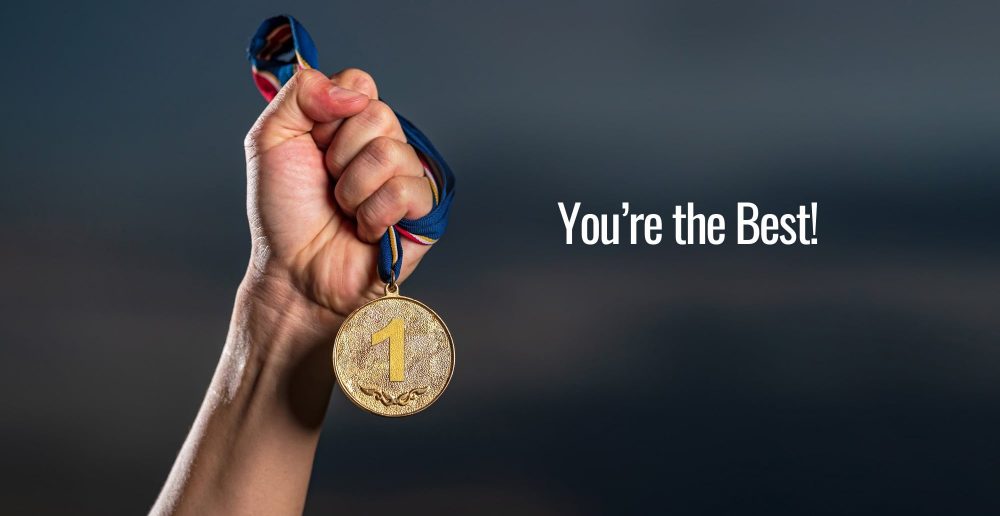 A close up of a person's left hand holding a gold medal